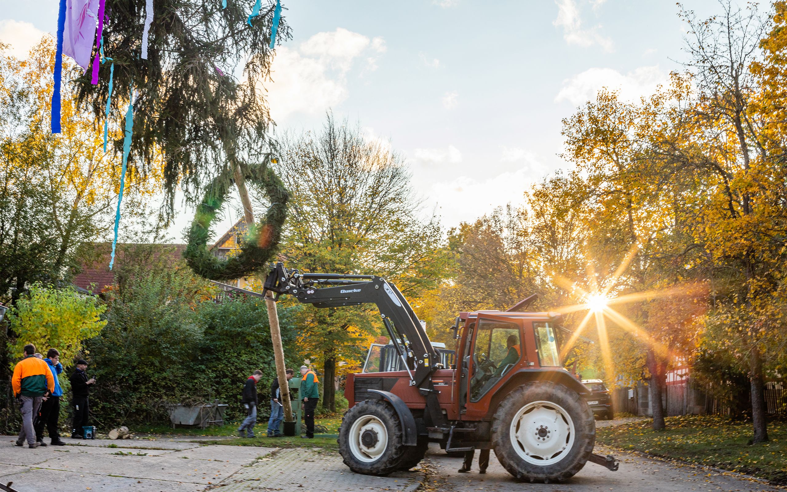 Ein Kirchweihbaum wird mit einem Traktor aufgestellt