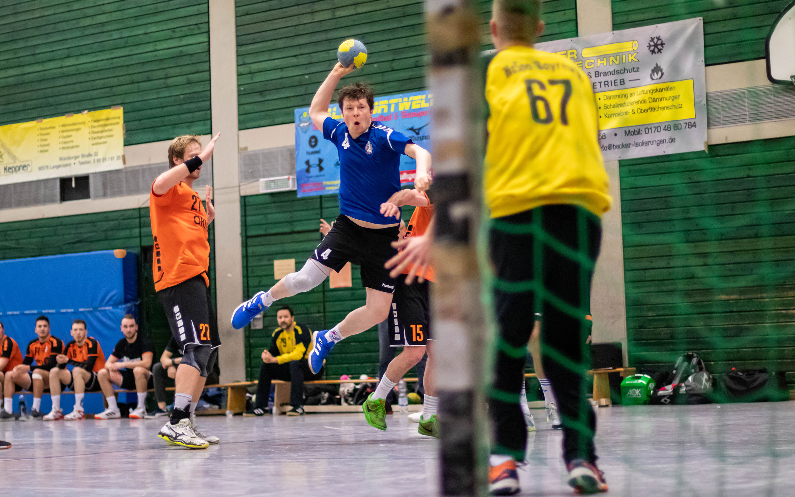 Ein Handballspieler wirft den Ball zum Tor und ist dabei in der Luft