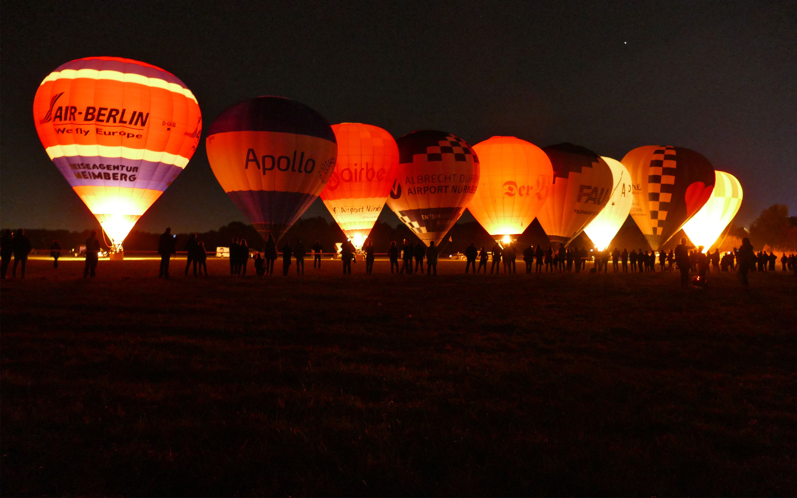 Heißluftballons leuchten in der Nacht im Wiesengrund