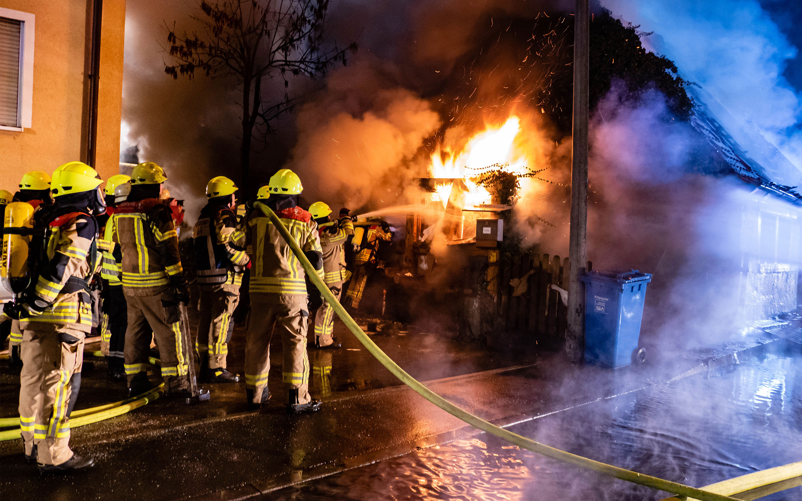Feuerwehrleute mit Atemschutz löschen einen Wohnhausbrand